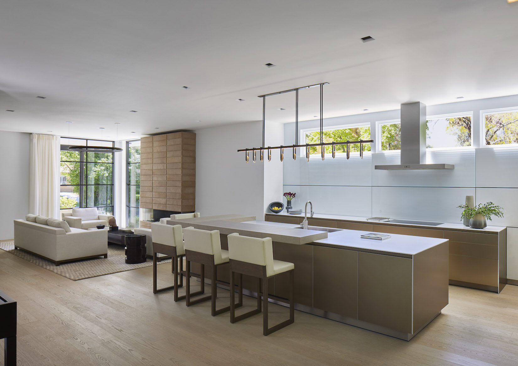 Timeless luxury kitchen design with open-plan layout, natural wood accents, and large windows by Kitchen Distributors